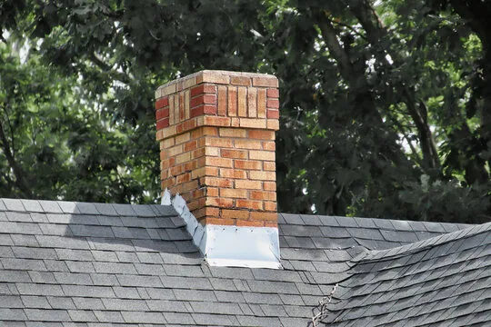 Two-tone brick chimney with flashing among trees
